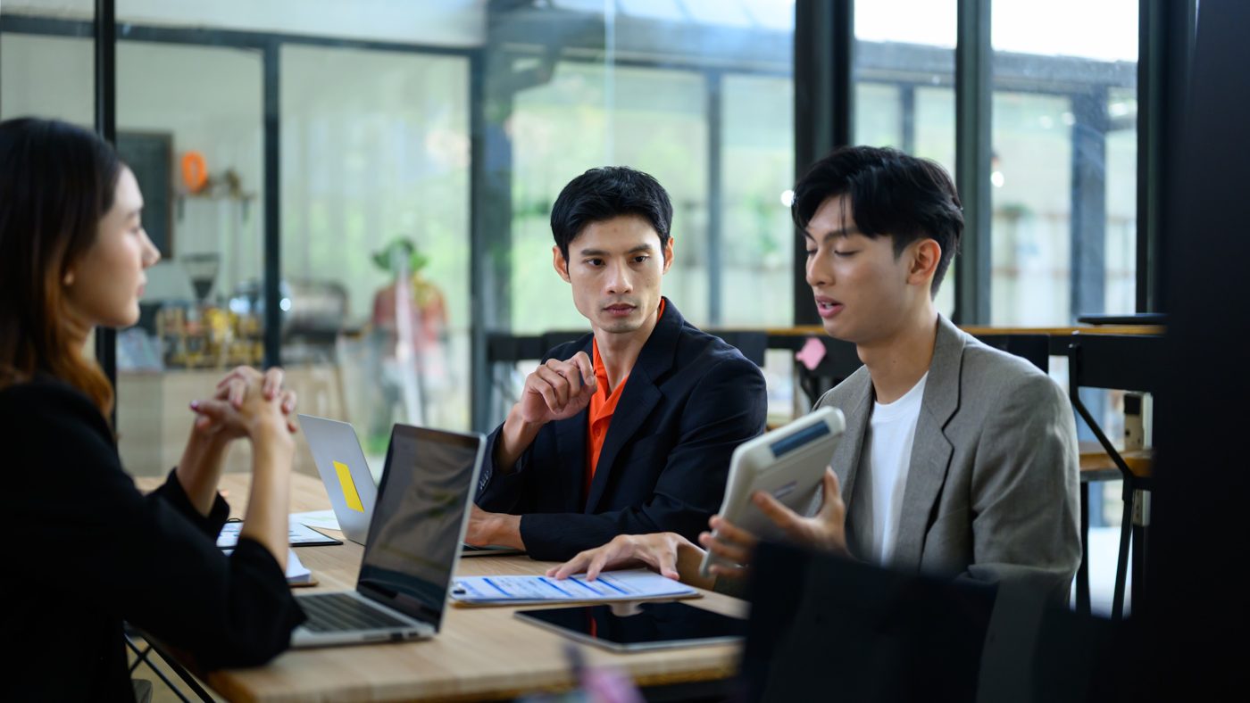 Colleagues discussing work at a table with laptops
